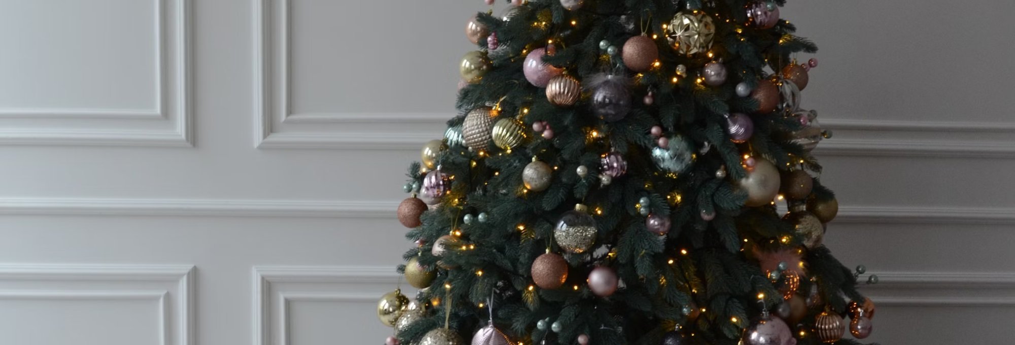 Christmas tree with neutral ornaments on a white wall background